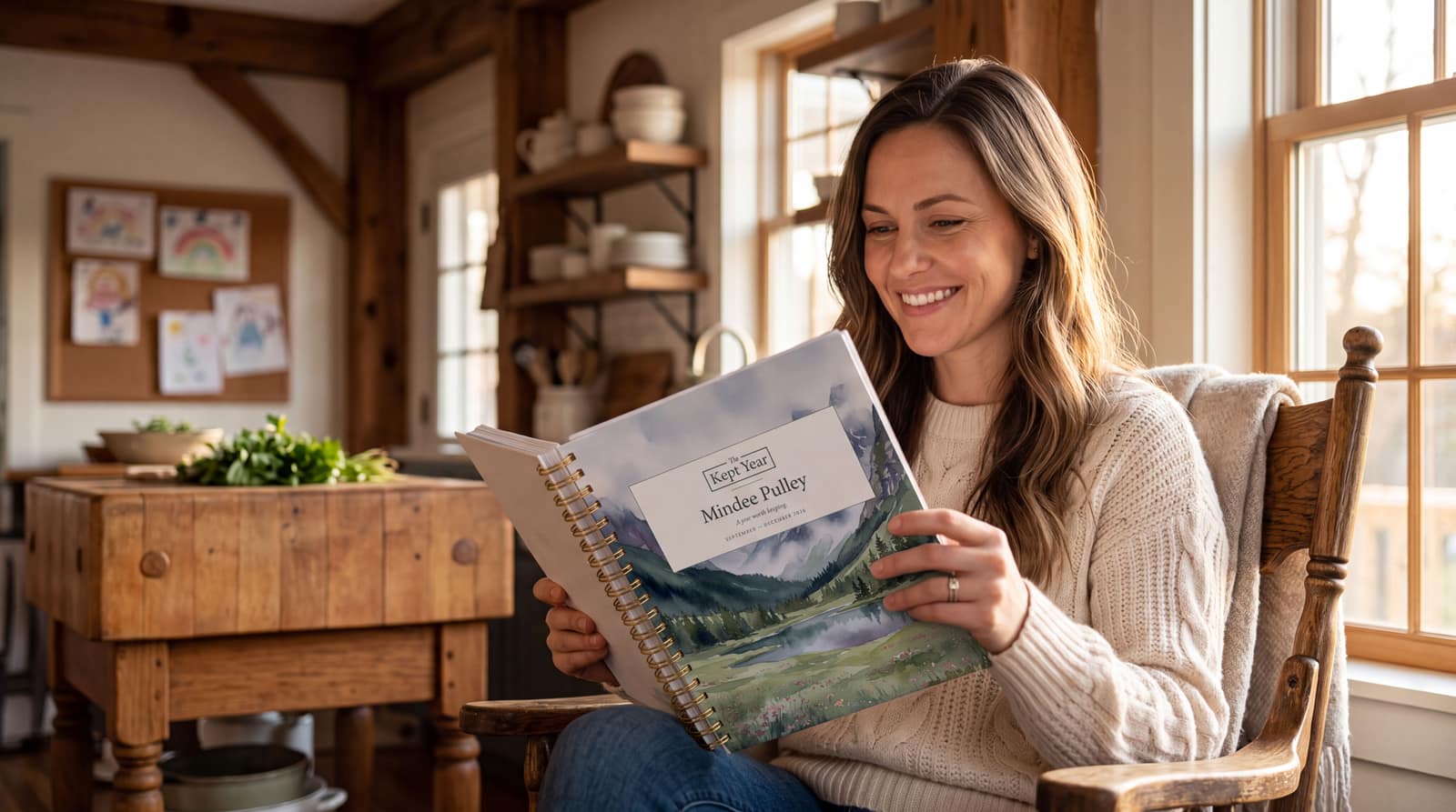 A woman in a rocking chair by a window, holding her own Kept Year planner